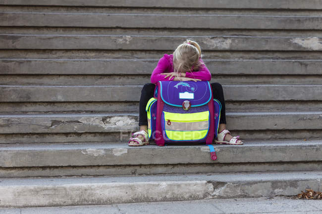 Ragazzina triste seduta sulle scale con la borsa della scuola — Foto stock
