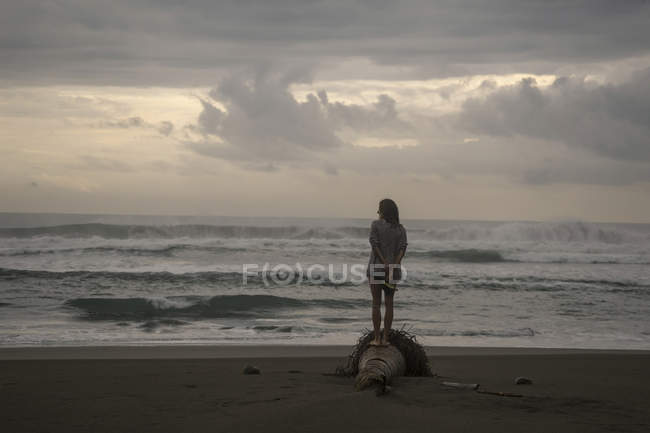 Indonésia, Java, mulher de pé na praia no crepúsculo da noite — Fotografia de Stock