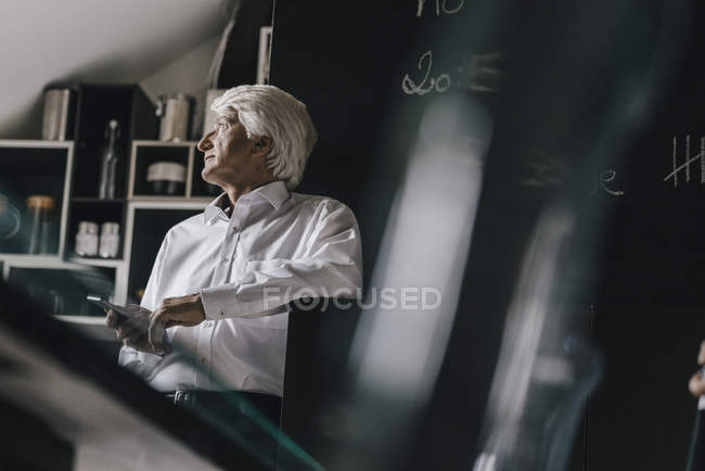Uomo d'affari anziano con smartphone in cucina — Foto stock