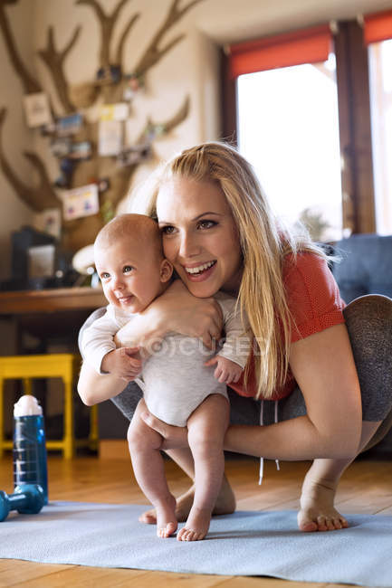 Lächelnde Mutter mit Baby und Fitnessgerät zu Hause — Stockfoto