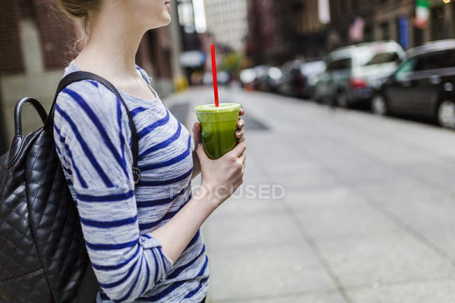 Portrait of young woman with smoothie at street — Stock Photo