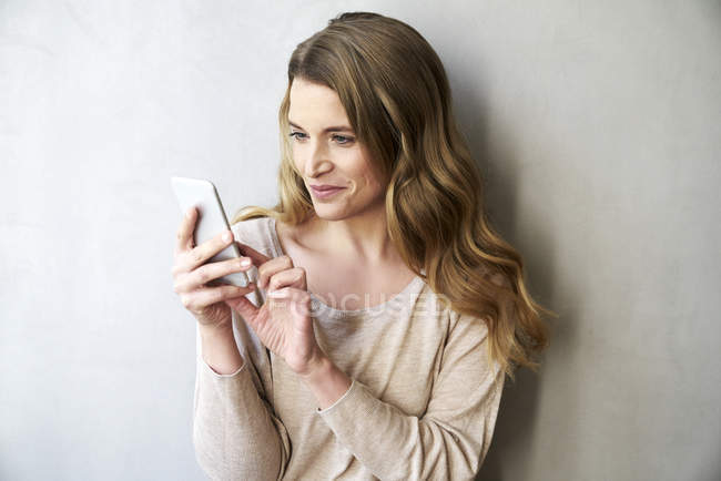 Portrait of smiling blond woman text messaging — Stock Photo