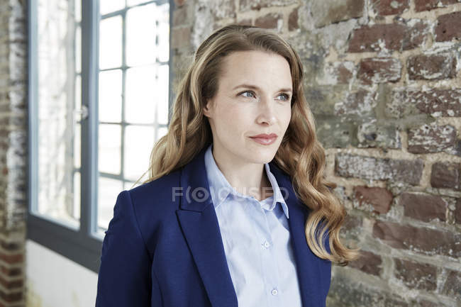 Portrait of businesswoman standing at brick wall — Stock Photo