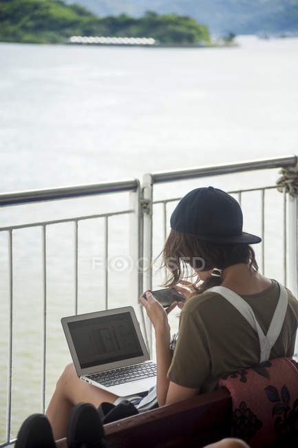 Indonésie, île de Lombok, femme utilisant un ordinateur portable et un téléphone portable sur le pont du navire — Photo de stock