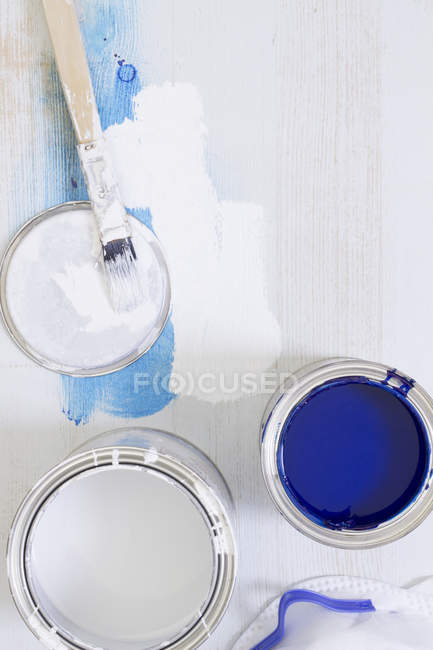 Used paint brush and paint tins with blue and white varnish — Stock Photo