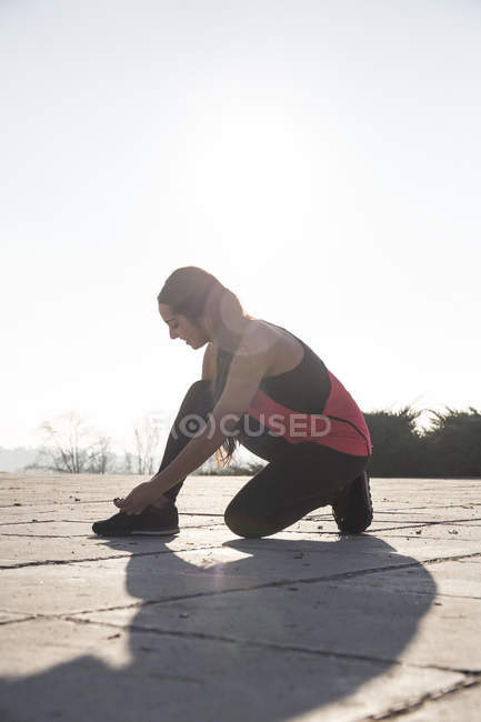 Junge Frau schnürt Schuhe vor dem Laufen — Stockfoto