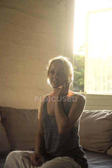 Блондинка по телефону сидит на диване на подсветке — стоковое фото