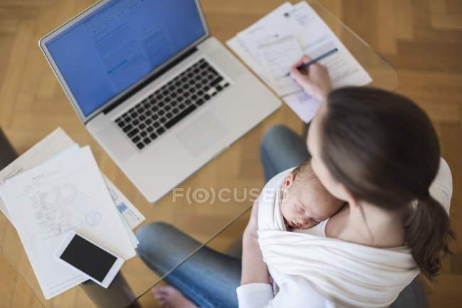 Erhöhter Blick auf freiberufliche Mutter mit Säugling im Tragetuch bei der Arbeit im Home Office — Stockfoto