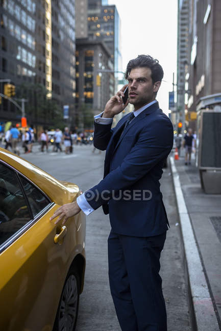 Empresário no telefone entrando táxi amarelo — Fotografia de Stock