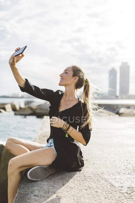 Glückliche junge Frau macht ein Selfie mit Handy am Meer — Stockfoto