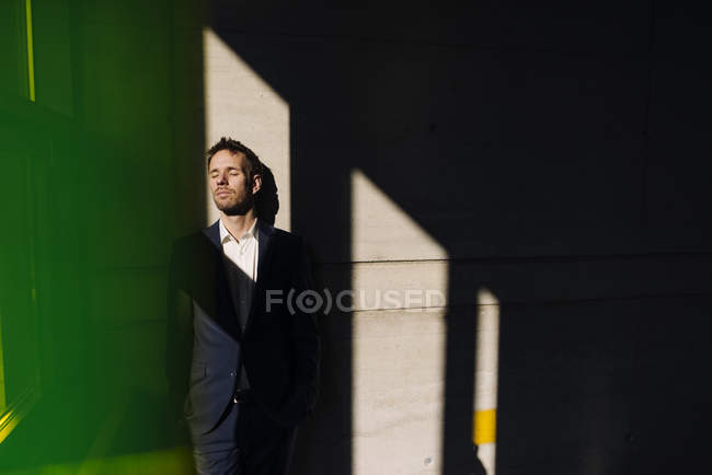 Portrait d'un homme d'affaires debout dans l'ombre près d'un mur — Photo de stock
