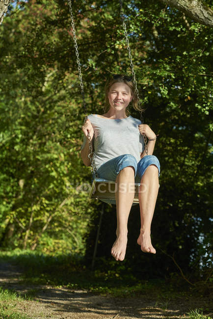 Sorrindo jovem mulher sentada no balanço — Fotografia de Stock