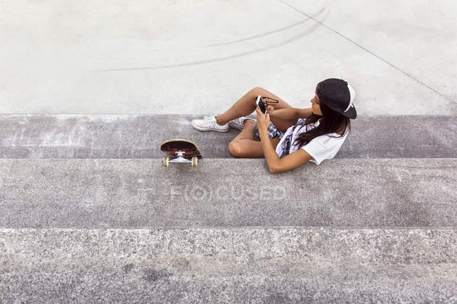 Gijn, Asturias, Spain, skateboarder girl sending messages with her smartphone — Stock Photo