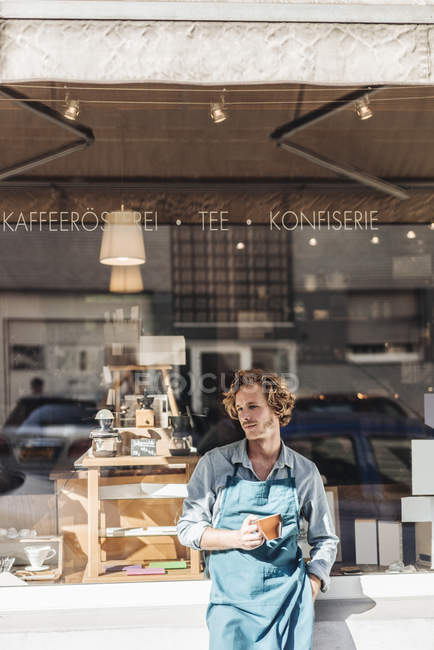 Kaffeeröster hält Tasse vor Geschäft — Stockfoto