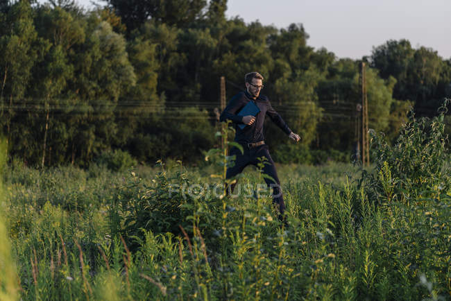 Portrait of businessman jumping in green field — Stock Photo