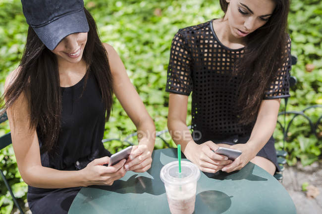 Twin sisters using cell phones — Stock Photo