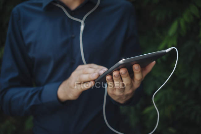 Обрезанный вид человека с помощью планшета с наушниками — стоковое фото