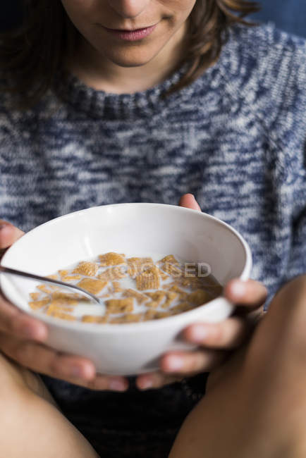 Jeune femme mangeant de l'avoine avec du lait pour le petit déjeuner à la maison — Photo de stock