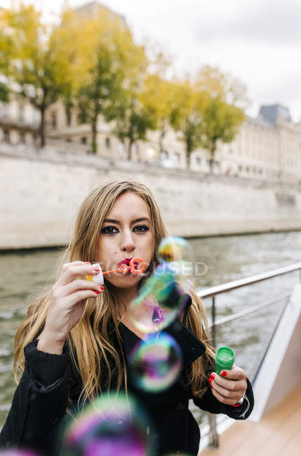 Paris, France, beautiful woman making soap bubbles over the Seine River — Stock Photo