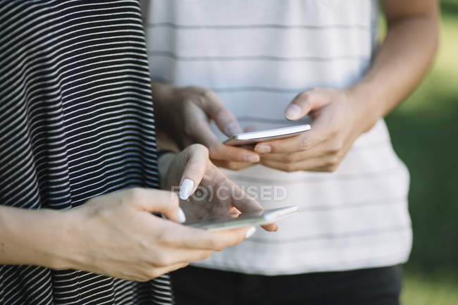 Manos de mujeres jóvenes sosteniendo teléfonos inteligentes - foto de stock