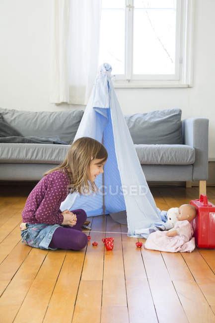 Маленькая девочка играет в кофейную вечеринку с игрушками на полу дома — стоковое фото