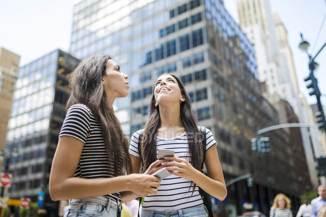 Twin sisters walking with cell phones — Stock Photo