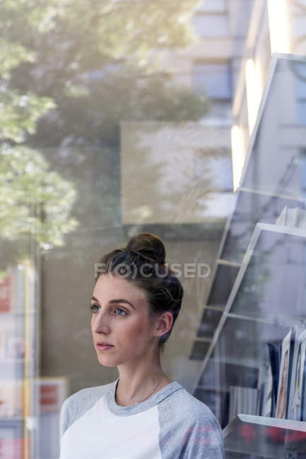 Woman looking through window in bookshop — Stock Photo