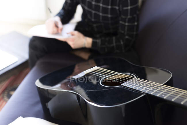Man writing notes, guitar on foreground — Stock Photo