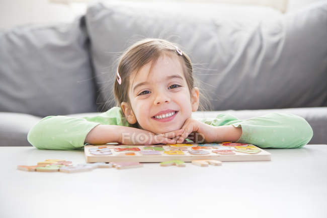 Retrato de niña sonriente con letras de madera en casa - foto de stock