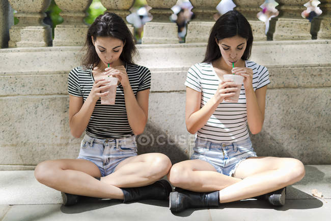 Twin sisters holding takeaway drinks — Stock Photo