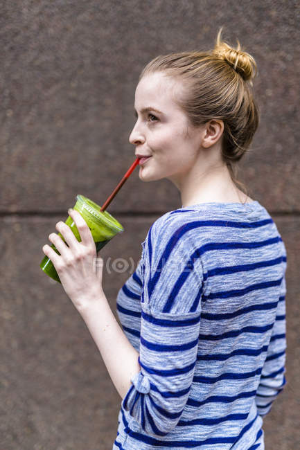 Ritratto di giovane donna che beve frullato verde — Foto stock