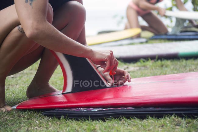 Nahaufnahme einer Frau, die ein Surfbrett auf einer Wiese präpariert — Stockfoto
