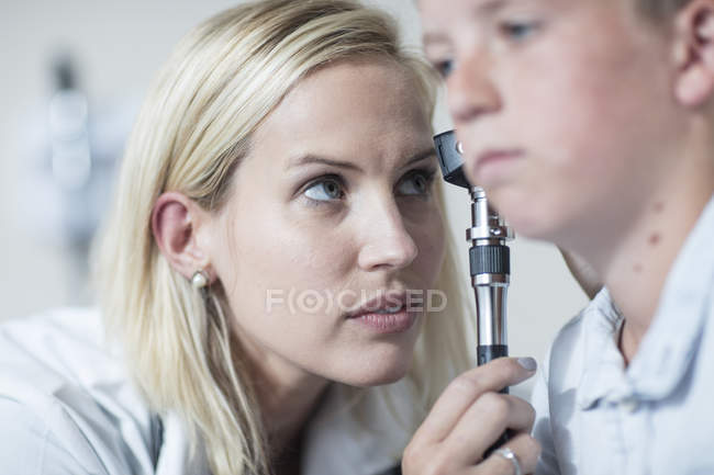 Femmina pedatrico esaminando ragazzo con un otoscopio — Foto stock