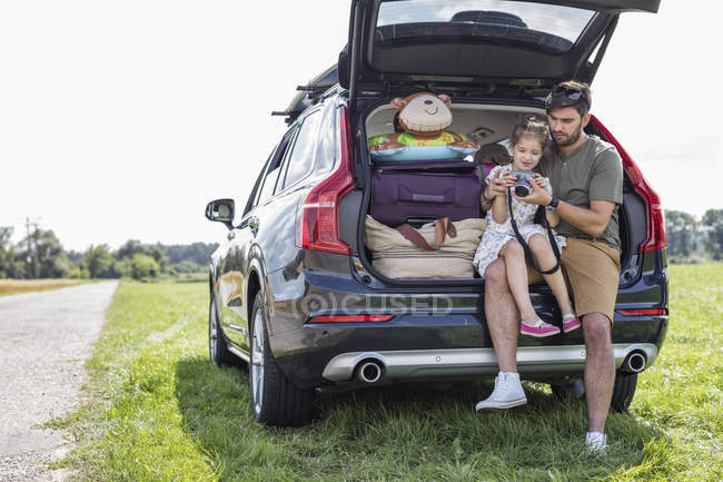 Padre e hija sentados en el maletero de coche abierto mirando la cámara — Stock Photo