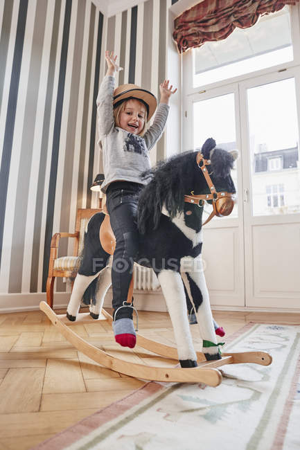 Menina feliz posando no cavalo de balanço — Fotografia de Stock