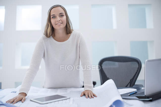 Woman standing at desk with digital tablet and laptop — Stock Photo