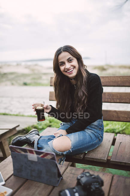 Усміхаючись молода жінка з скла кола, сидячи в придорожньому кафе — стокове фото