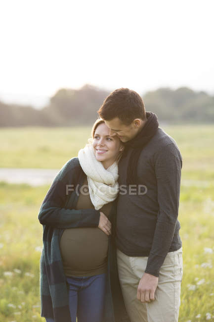 Felices padres expectantes en el paisaje rural - foto de stock