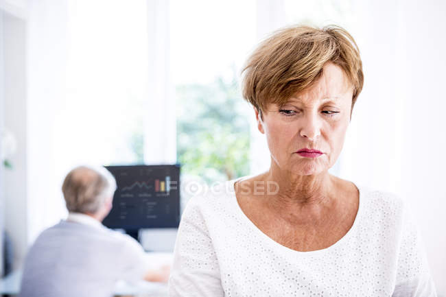 Ritratto donna triste, uomo anziano a tavola con computer sullo sfondo — Foto stock