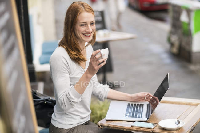 Mignonne rousse caucasienne femme en utilisant un ordinateur portable au café — Photo de stock