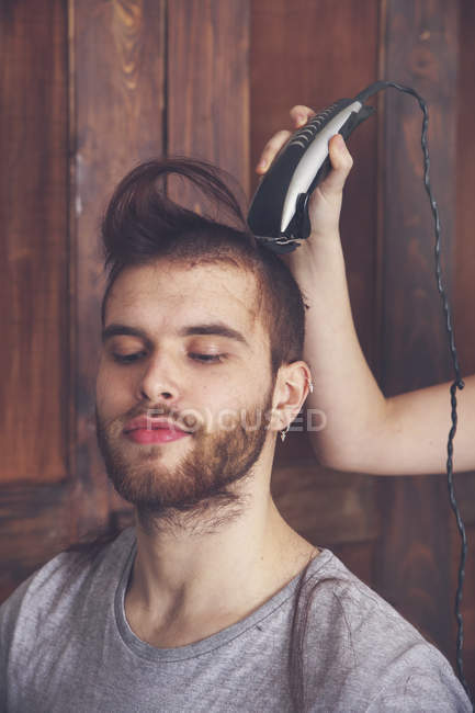Portrait Of Young Man Getting A Haircut By His Girlfriend