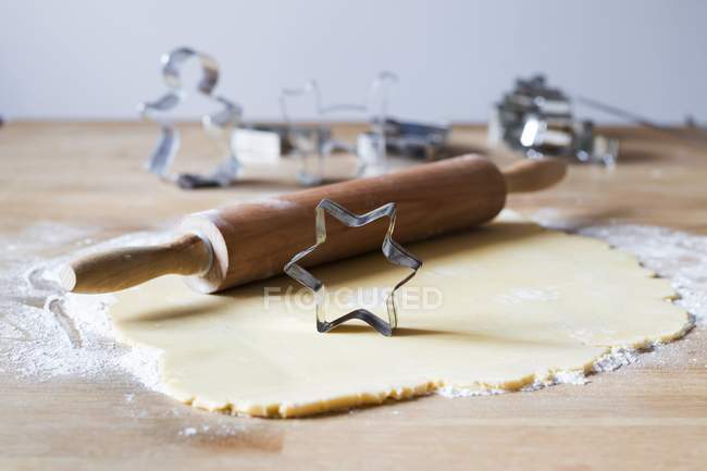 Nahaufnahme von gewalztem Teig mit Nudelholz und sternförmigem Ausstecher auf Mehl — Stockfoto