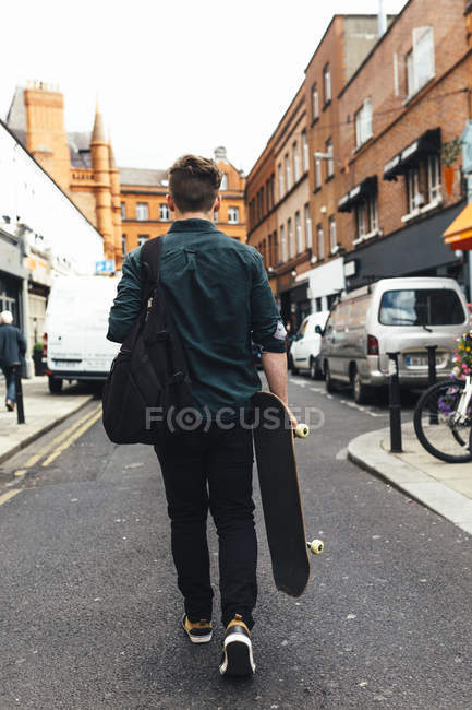 Rear view of young man with skateboard in Dublin, Ireland — Stock Photo