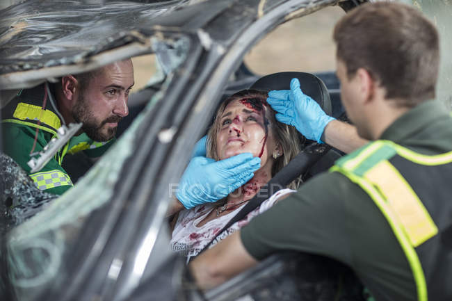 Les ambulanciers aident la victime de l'accident de voiture après l'accident — Photo de stock