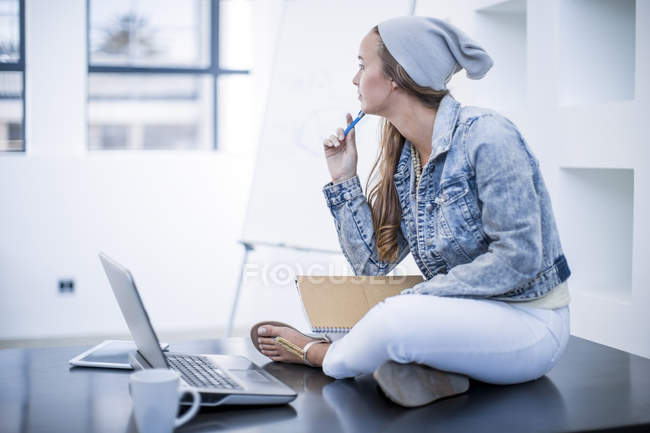 Nachdenkliche Frau sitzt mit Laptop am Schreibtisch im Büro — Stockfoto