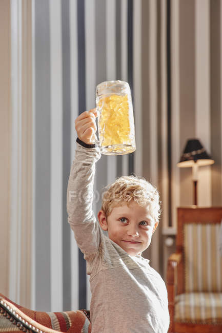 Boy raising fruit gum beer mug — Stock Photo