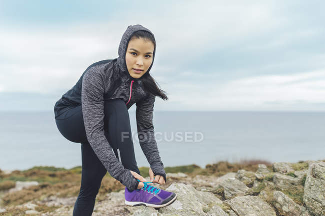 Irlande, Howth, femme lacer ses chaussures à falaise côte — Photo de stock