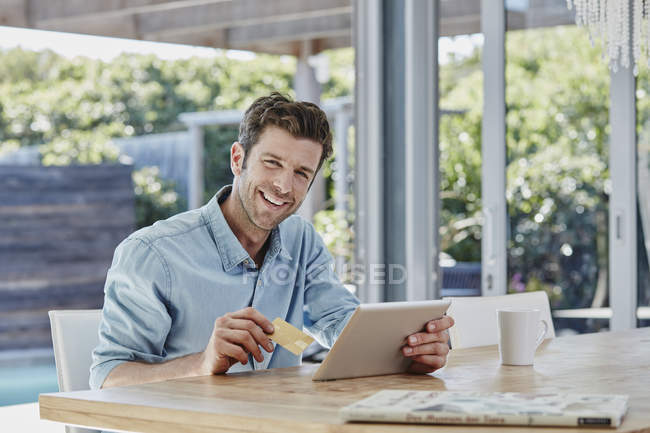Портрет улыбающегося человека с помощью планшета за столом — стоковое фото
