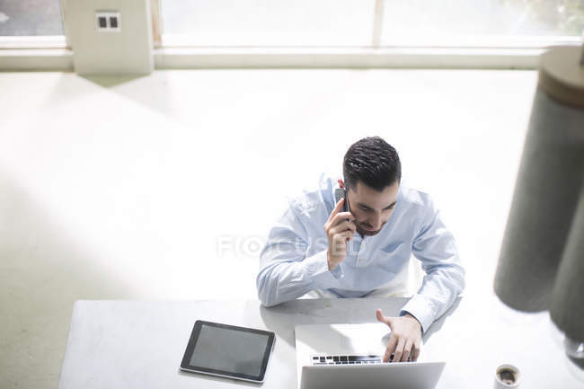 Hombre sentado detrás de la computadora en la oficina de diseño de hormigón moderno - foto de stock