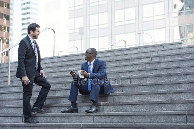 Dois empresários sorridentes conversando nas escadas — Fotografia de Stock